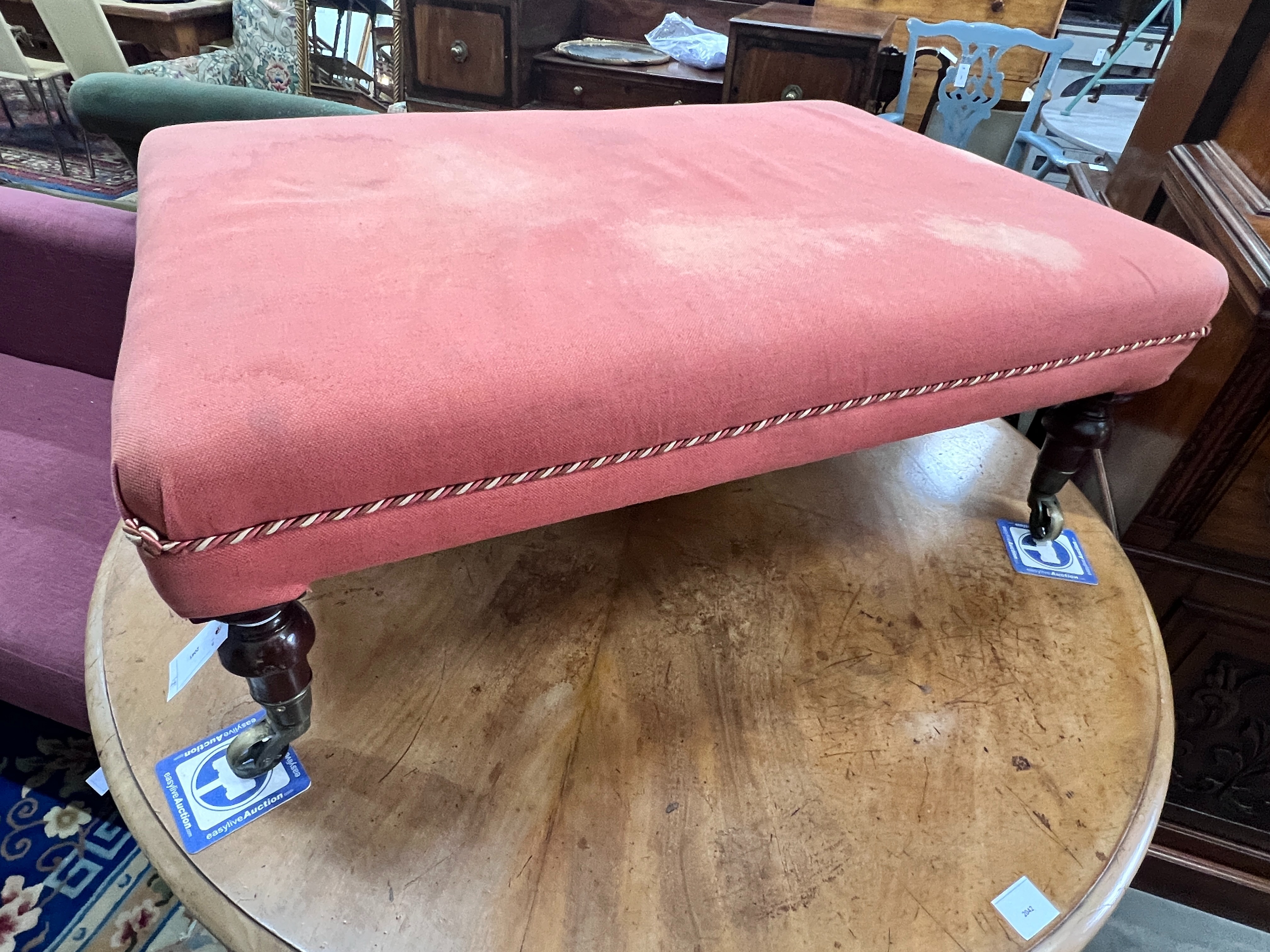 A Victorian rectangular stool on turned mahogany legs with spoked castors, length 93cm, width 64cm, height 35cm